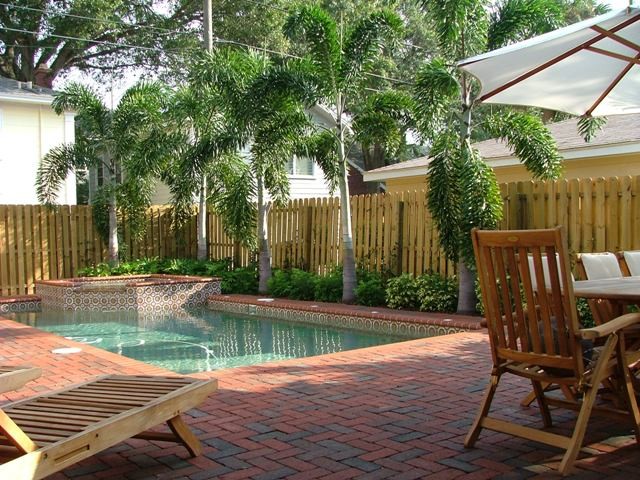 Inspiration for a small back rectangular natural hot tub in Tampa with brick paving.