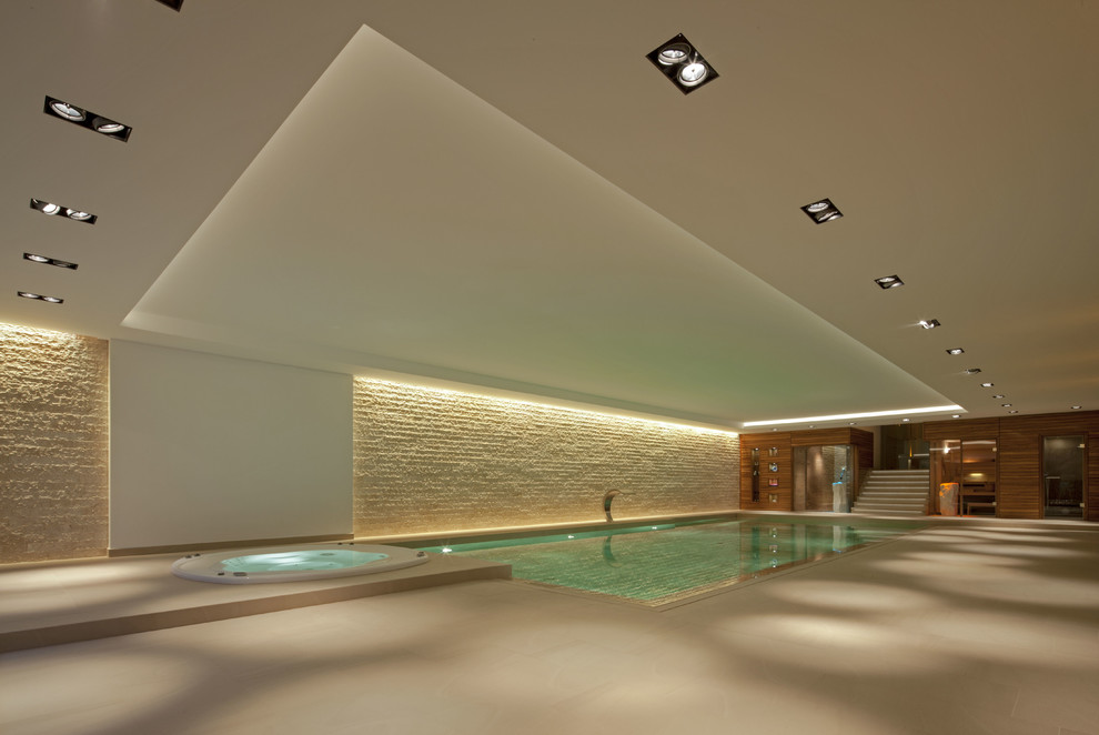 Exemple d'une grande piscine intérieure tendance rectangle avec un bain bouillonnant et des pavés en béton.
