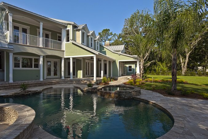 Idee per una grande piscina naturale design a "C" dietro casa con una vasca idromassaggio e pavimentazioni in pietra naturale
