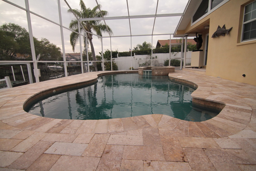 На фото: большой бассейн в форме фасоли на заднем дворе в средиземноморском стиле с джакузи и покрытием из декоративного бетона с