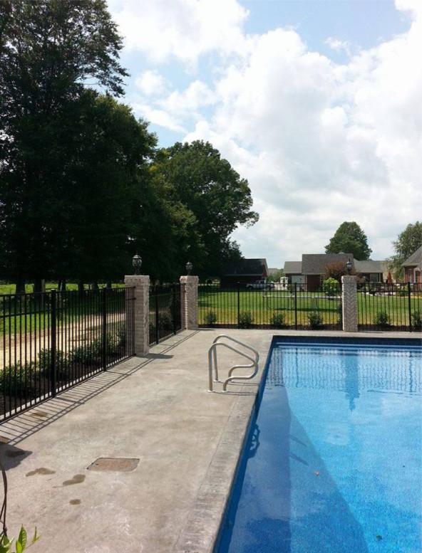 Diseño de casa de la piscina y piscina alargada tradicional grande rectangular en patio trasero con losas de hormigón