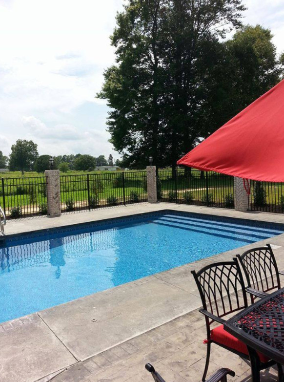 Foto de piscina alargada tradicional grande rectangular en patio trasero con losas de hormigón
