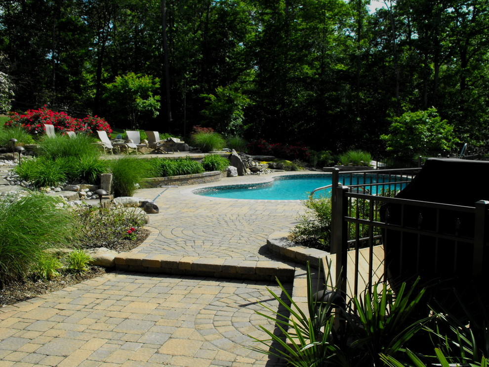 Immagine di una piscina tradizionale personalizzata di medie dimensioni e dietro casa con fontane e pavimentazioni in cemento