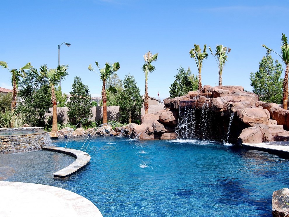 Immagine di una grande piscina chic personalizzata dietro casa con un acquascivolo e lastre di cemento