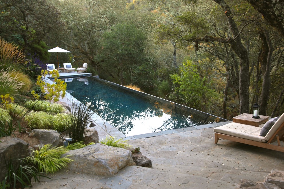 Photo of a large contemporary back rectangular infinity swimming pool in San Francisco with natural stone paving.