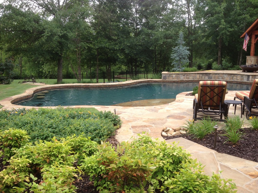 Esempio di un'ampia piscina naturale classica personalizzata dietro casa con fontane e pavimentazioni in pietra naturale