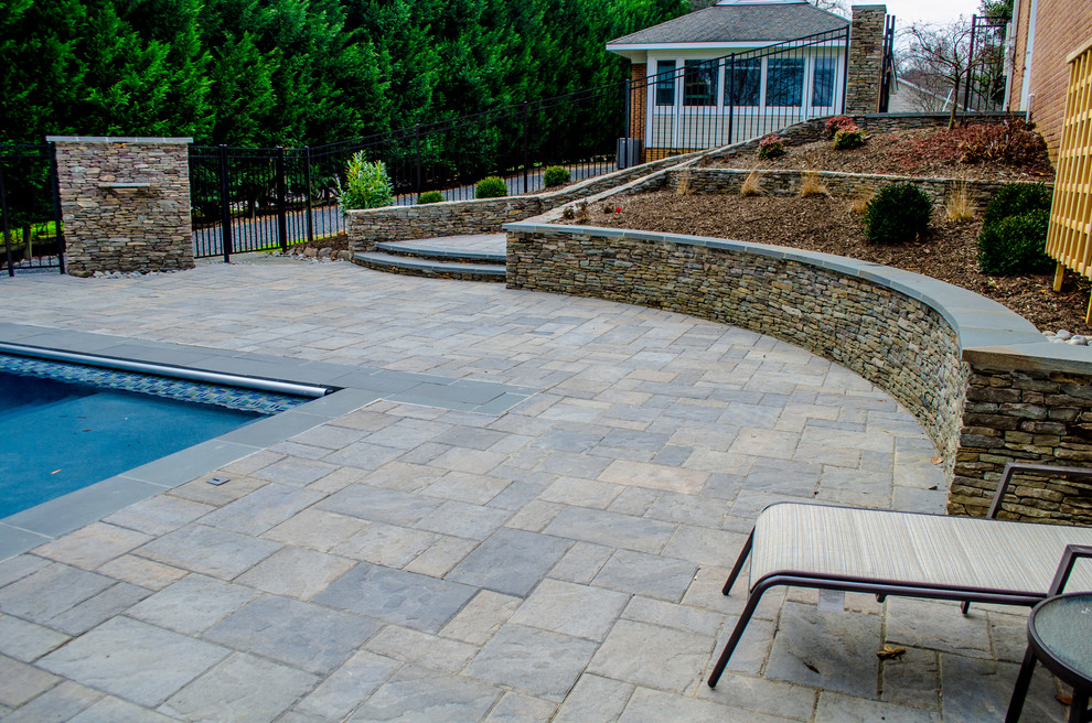 Modelo de piscina clásica renovada grande rectangular en patio trasero con adoquines de hormigón