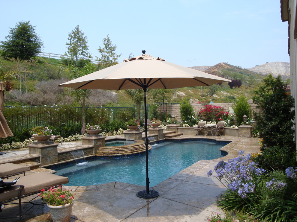 Пример оригинального дизайна: бассейн среднего размера, произвольной формы на заднем дворе в классическом стиле с фонтаном и мощением тротуарной плиткой
