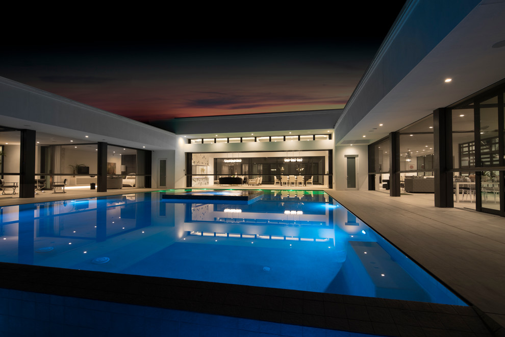 Ispirazione per una grande piscina minimalista rettangolare dietro casa con una vasca idromassaggio e piastrelle
