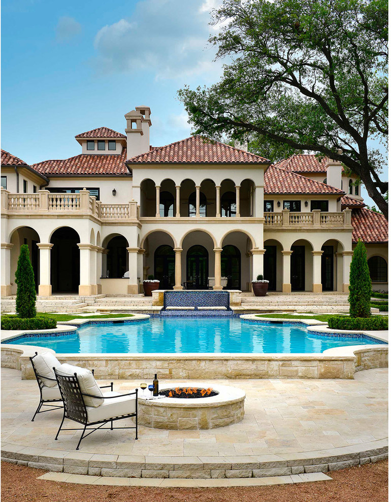 Ispirazione per una grande piscina mediterranea personalizzata dietro casa con pavimentazioni in pietra naturale e una vasca idromassaggio