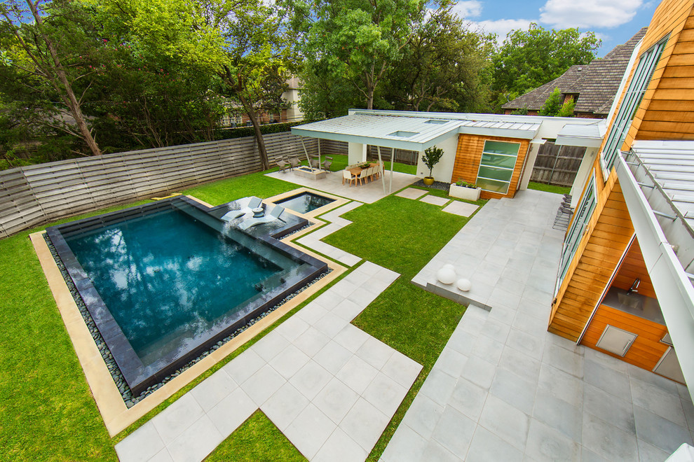 Cette image montre une grande piscine arrière minimaliste rectangle avec un bain bouillonnant et du carrelage.