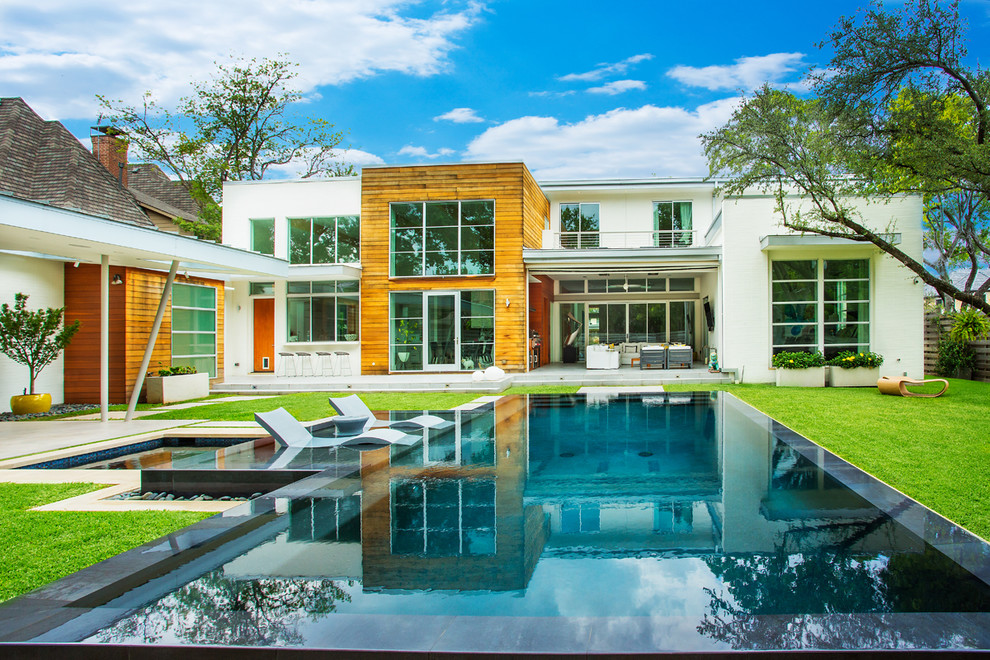 Foto di una grande piscina a sfioro infinito contemporanea rettangolare dietro casa con una vasca idromassaggio