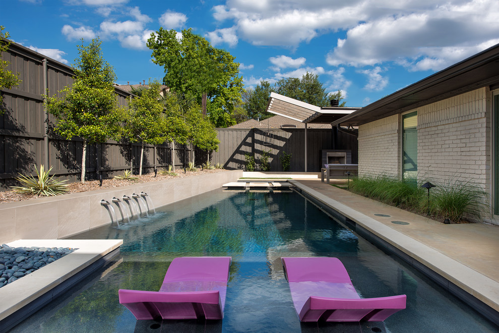Immagine di una piscina moderna rettangolare di medie dimensioni e dietro casa con lastre di cemento e fontane