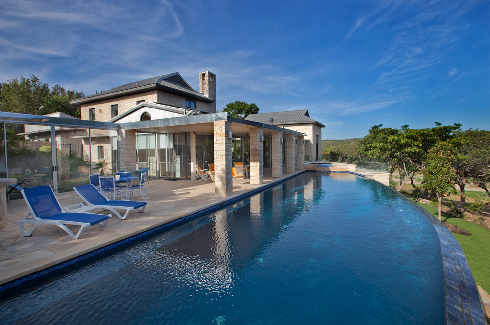 Idée de décoration pour une piscine à débordement design sur mesure avec des pavés en pierre naturelle.