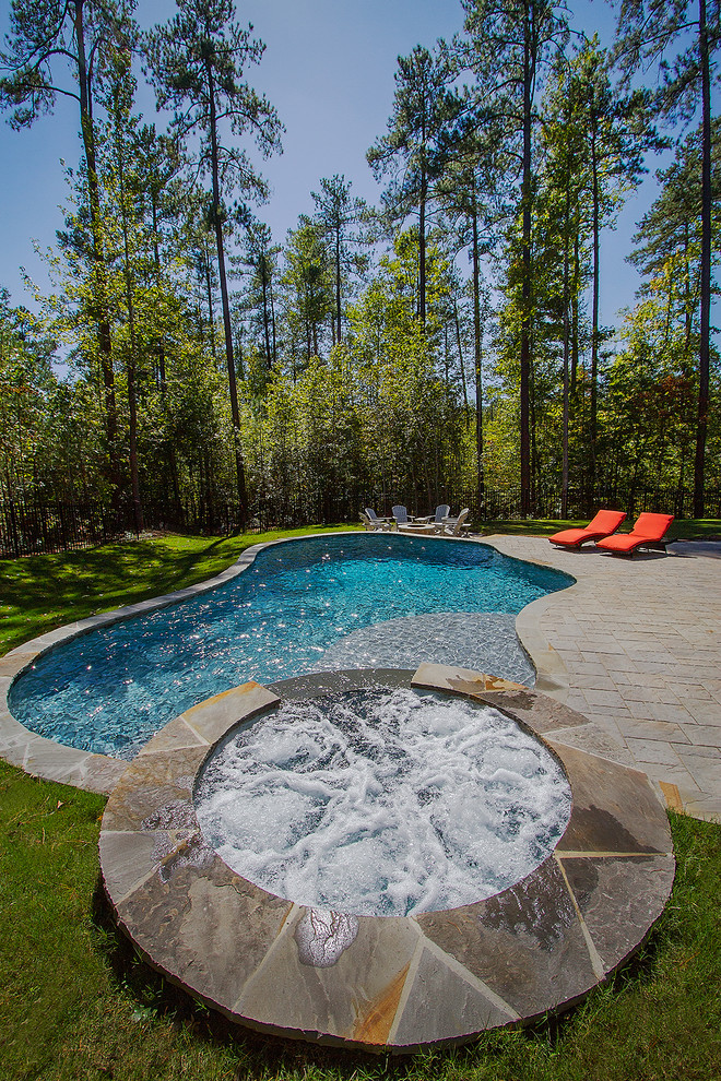 На фото: естественный бассейн среднего размера, произвольной формы на заднем дворе в стиле рустика с джакузи и мощением тротуарной плиткой