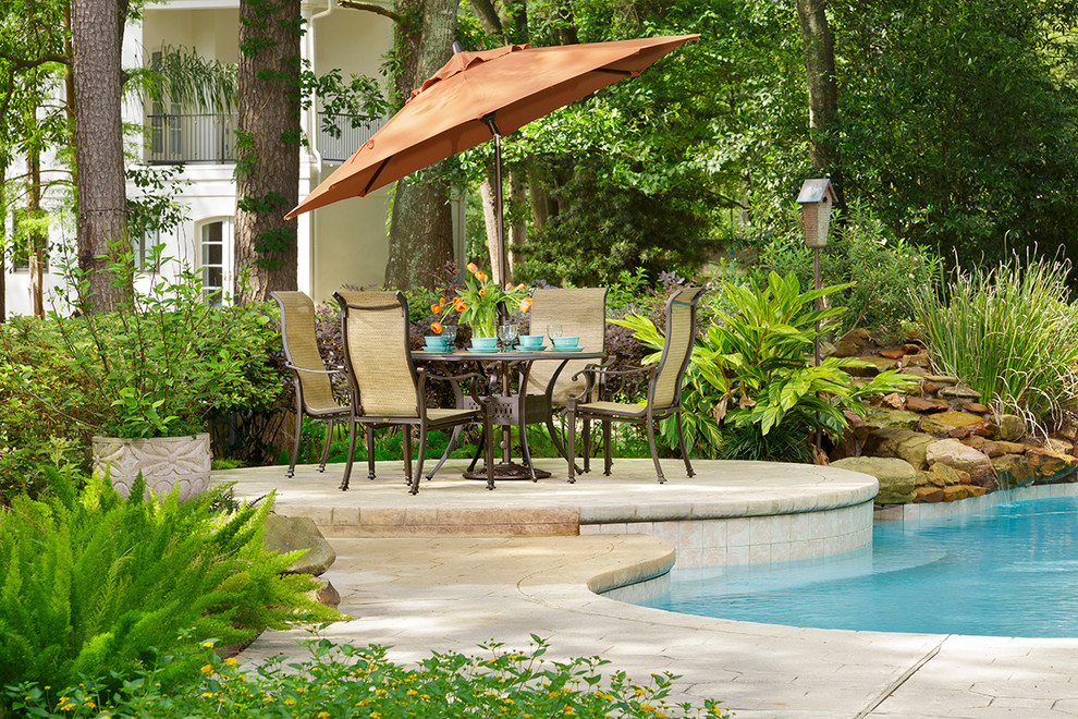 Diseño de piscina con fuente tradicional a medida en patio trasero con suelo de hormigón estampado