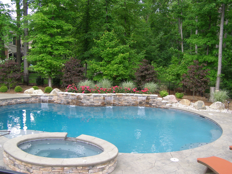 Exemple d'une piscine hors-sol et arrière chic en forme de haricot de taille moyenne avec un bain bouillonnant et des pavés en pierre naturelle.