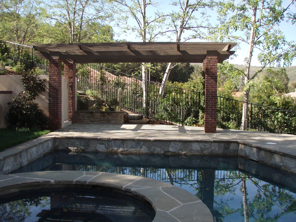На фото: бассейн среднего размера, произвольной формы на заднем дворе в стиле лофт с джакузи и покрытием из каменной брусчатки
