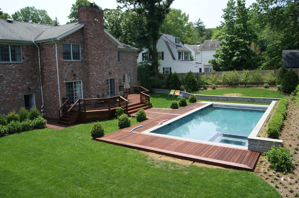 Ispirazione per un'ampia piscina a sfioro infinito design rettangolare dietro casa con una vasca idromassaggio e pedane