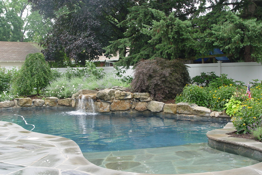 Cette photo montre une piscine naturelle et arrière moderne de taille moyenne et sur mesure avec un point d'eau et des pavés en pierre naturelle.