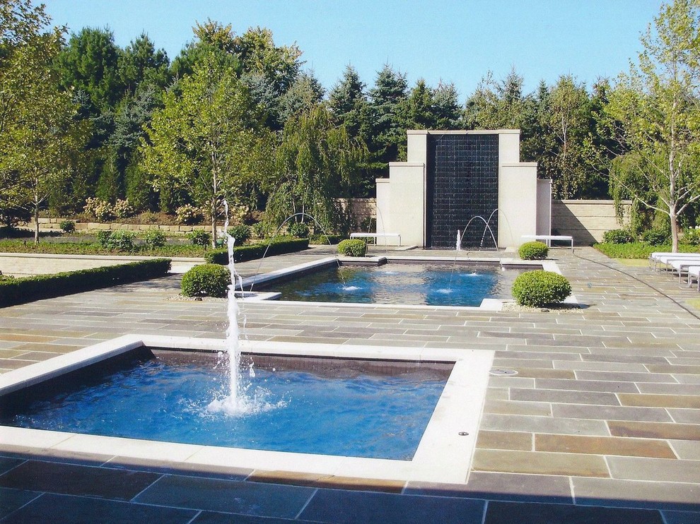 Imagen de piscina con fuente tradicional de tamaño medio rectangular en patio trasero con adoquines de piedra natural