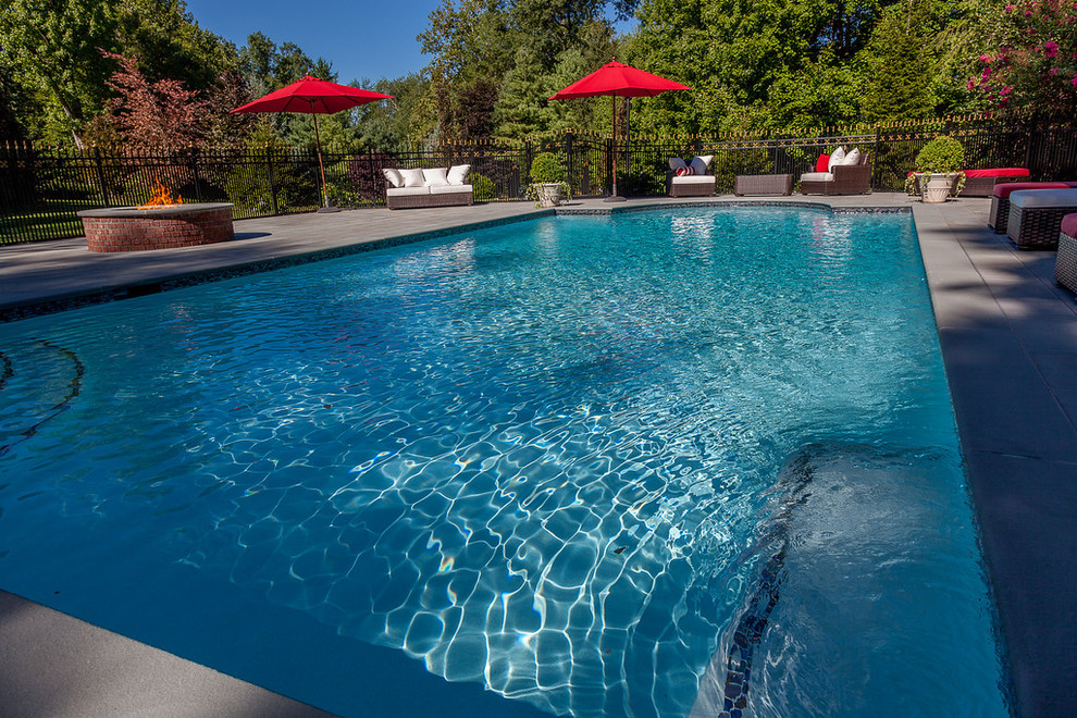 Foto de piscina con fuente alargada clásica grande a medida en patio trasero con adoquines de hormigón