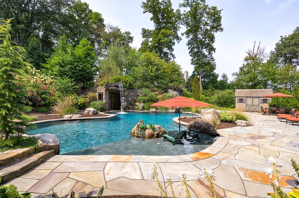 Cette image montre une piscine arrière traditionnelle sur mesure avec un point d'eau et des pavés en pierre naturelle.