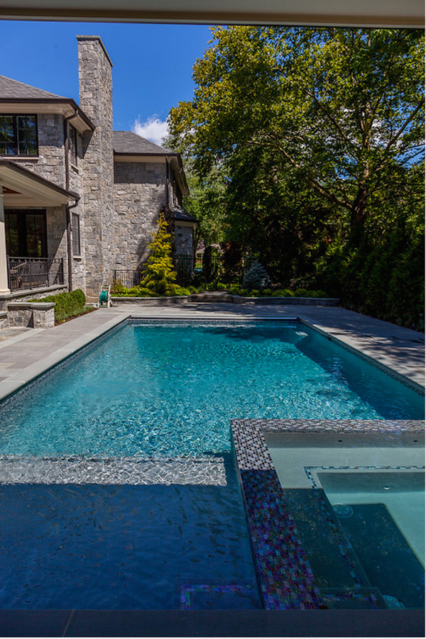 Ispirazione per una grande piscina monocorsia tradizionale rettangolare dietro casa con pavimentazioni in pietra naturale e fontane