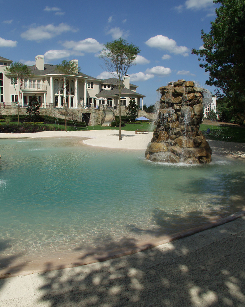 Foto på en mycket stor tropisk pool på baksidan av huset, med en fontän