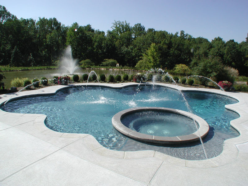Aménagement d'une très grande piscine naturelle et arrière classique sur mesure avec un bain bouillonnant et une dalle de béton.