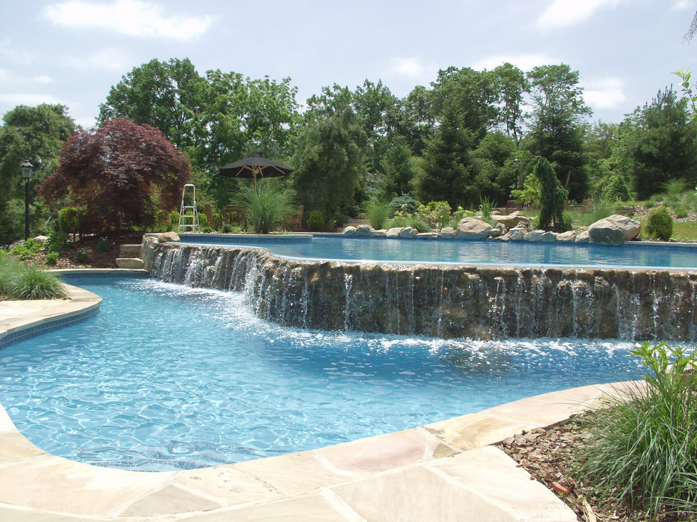 Esempio di un'ampia piscina a sfioro infinito country personalizzata dietro casa con pavimentazioni in pietra naturale e una vasca idromassaggio