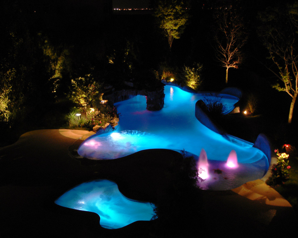 Foto de piscina con fuente alargada exótica grande a medida en patio trasero con losas de hormigón