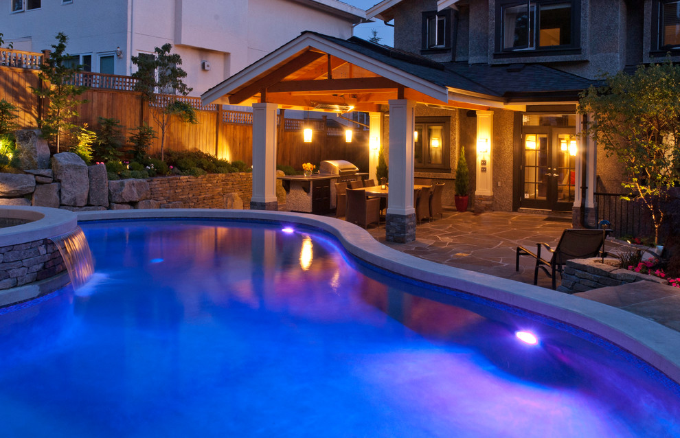 Mid-sized elegant backyard stone and custom-shaped hot tub photo in Vancouver