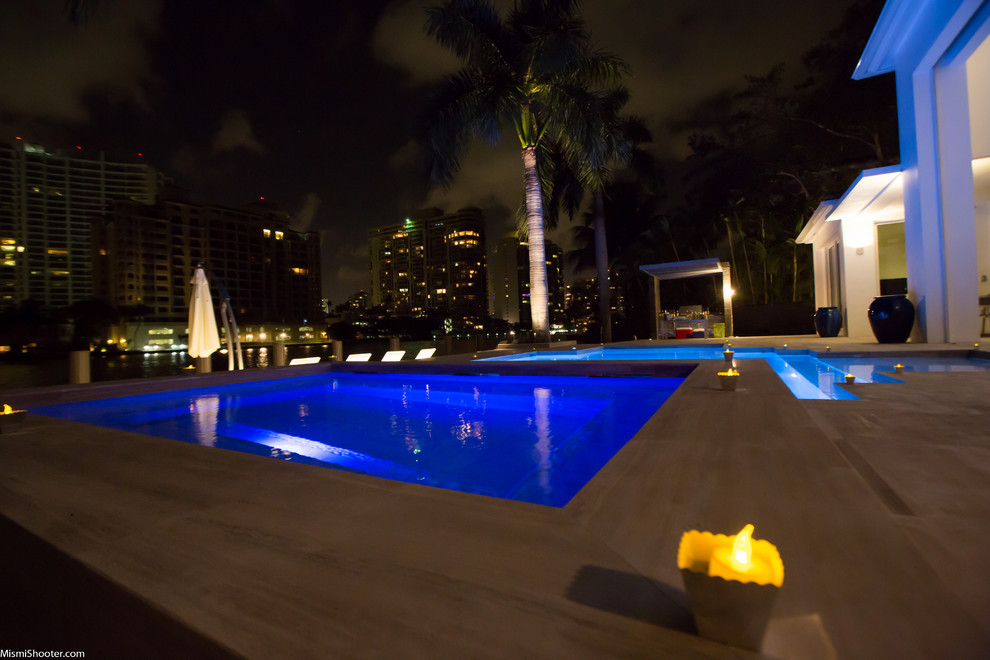 This is an example of a medium sized contemporary back custom shaped natural swimming pool in Miami with tiled flooring.