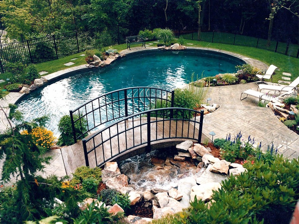 Ejemplo de piscina con fuente natural tradicional de tamaño medio a medida en patio trasero con adoquines de piedra natural