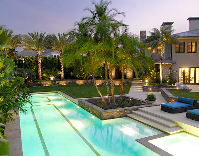 Ispirazione per una grande piscina monocorsia tropicale rettangolare dietro casa con una vasca idromassaggio e pavimentazioni in cemento