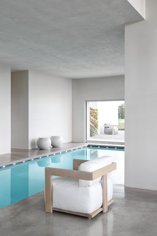 Réalisation d'une piscine intérieure design rectangle avec des pavés en béton.