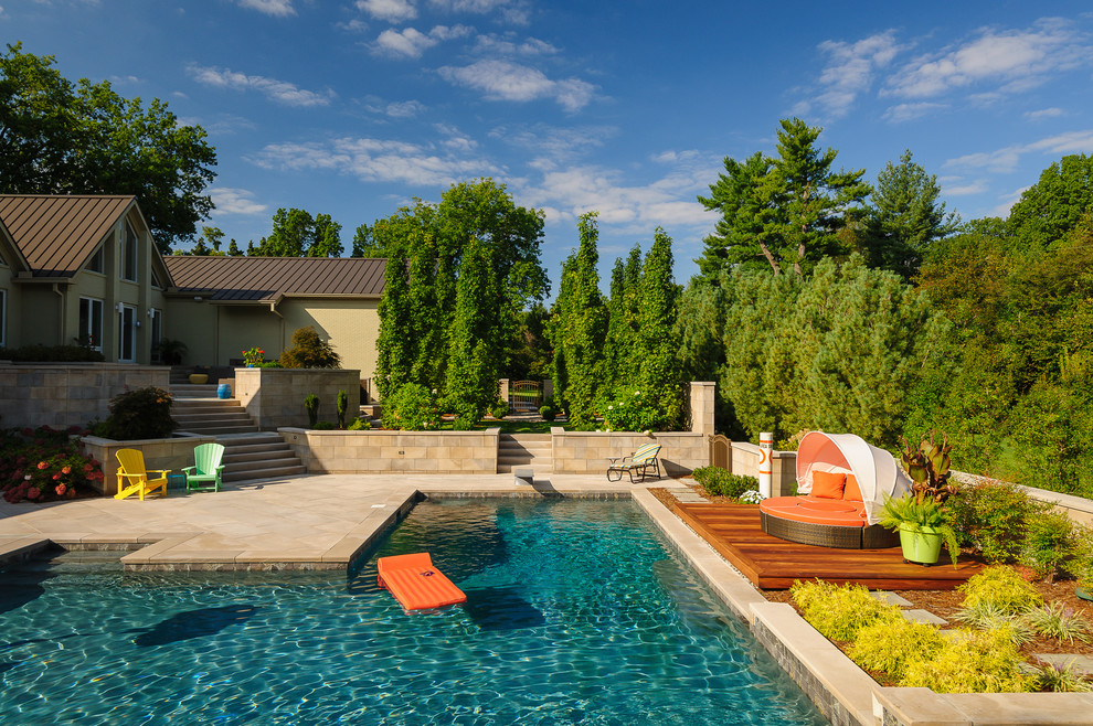 Foto de piscina actual de tamaño medio en forma de L en patio trasero con adoquines de piedra natural