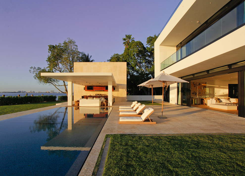 Ispirazione per una grande piscina a sfioro infinito minimalista rettangolare dietro casa con piastrelle