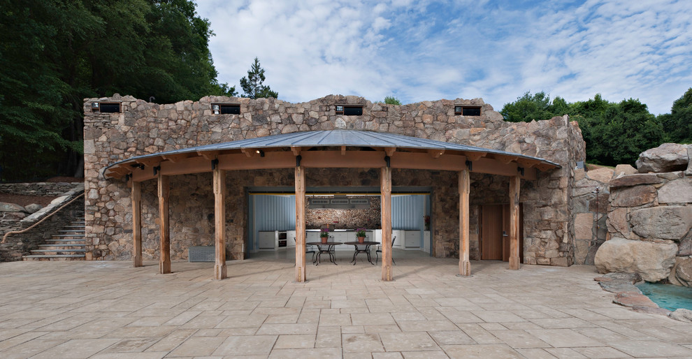 Ejemplo de casa de la piscina y piscina natural rústica grande a medida en patio trasero con adoquines de piedra natural