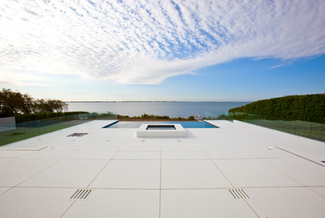 Esempio di una piscina a sfioro infinito moderna rettangolare di medie dimensioni e dietro casa con fontane e lastre di cemento