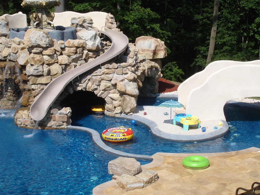 Ejemplo de piscina con tobogán contemporánea grande a medida en patio trasero con adoquines de piedra natural