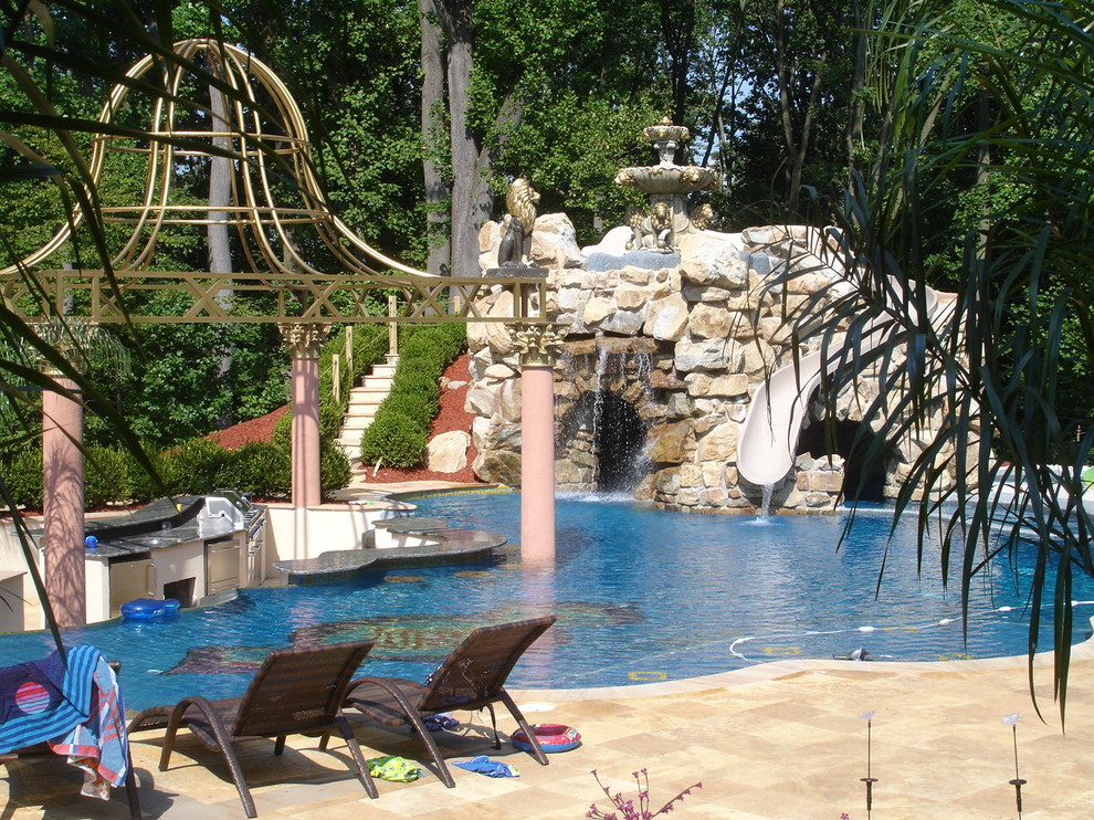 Modelo de piscina con tobogán actual grande a medida en patio trasero con adoquines de piedra natural