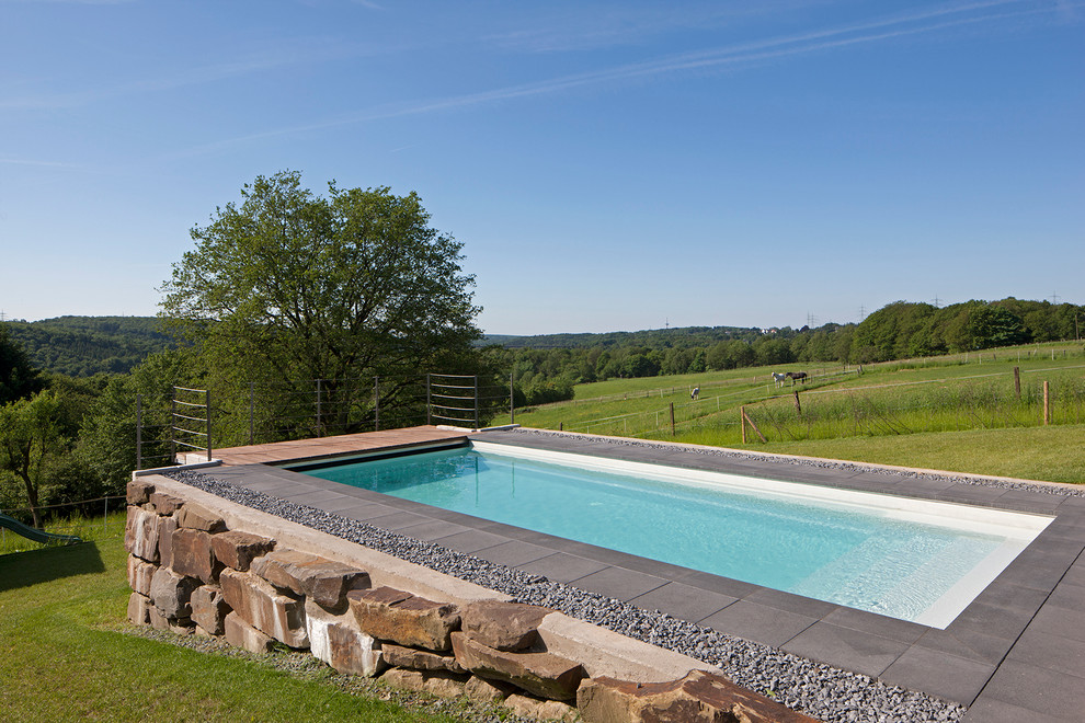 Diseño de piscina alargada actual de tamaño medio rectangular con losas de hormigón