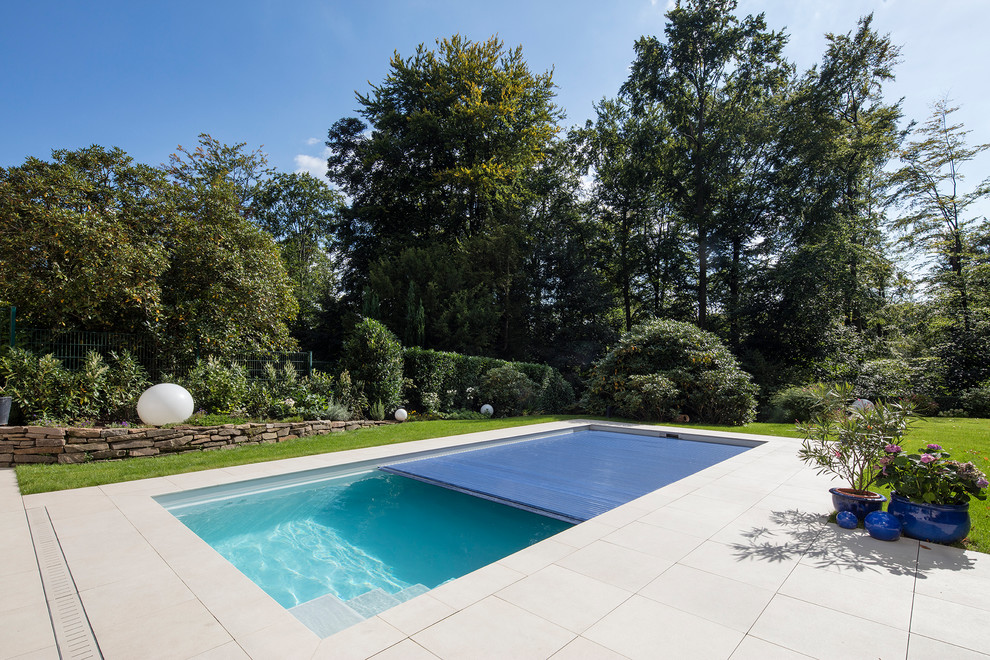 Medium sized traditional rectangular lengths swimming pool in Dusseldorf with concrete slabs.
