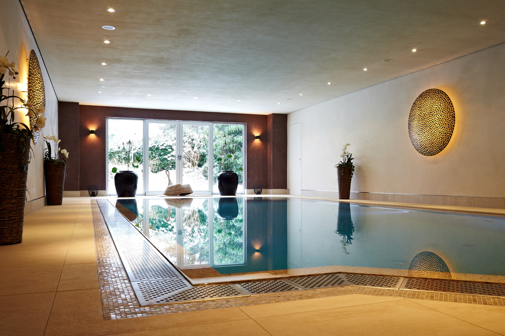 Idée de décoration pour une grande piscine intérieure design sur mesure avec une dalle de béton.