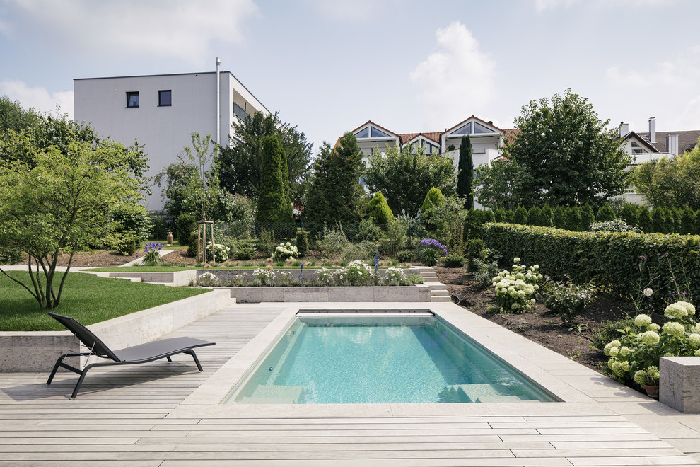 Immagine di una piscina minimal rettangolare con pavimentazioni in pietra naturale