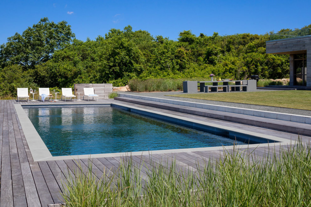 Ejemplo de piscina alargada actual grande rectangular en patio trasero con losas de hormigón