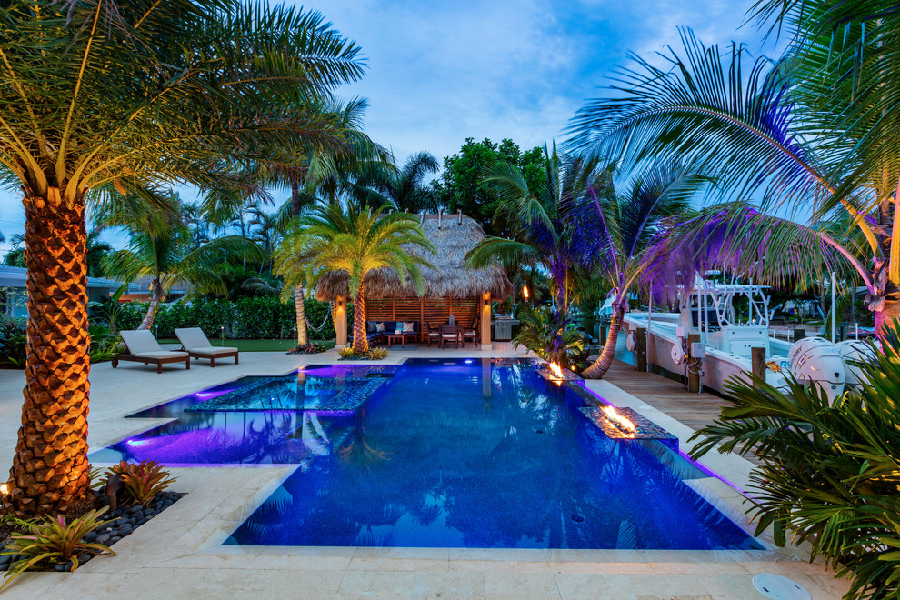 Foto de piscinas y jacuzzis infinitos tropicales de tamaño medio rectangulares en patio trasero con adoquines de piedra natural