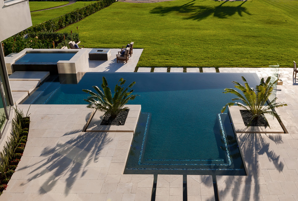 Modelo de piscinas y jacuzzis infinitos modernos grandes a medida en patio trasero con adoquines de piedra natural